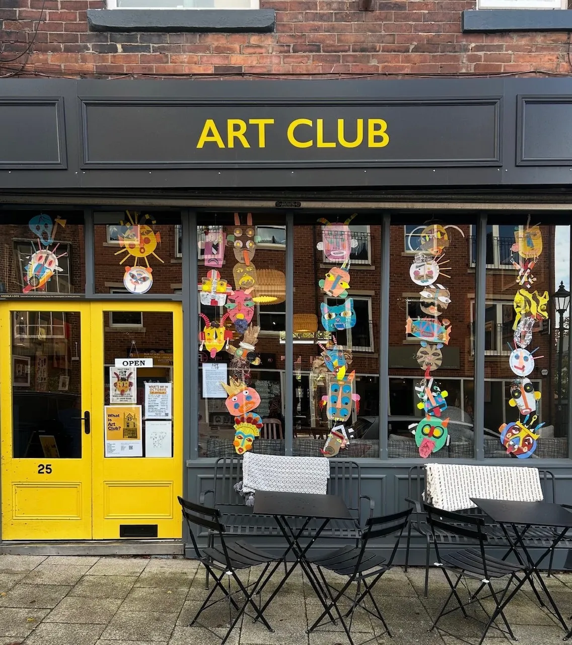 The Art Club storefront at 25 Shaw Road — yellow doors and 'ART CLUB' sign, with children's artwork in the windows and cafe tables outside